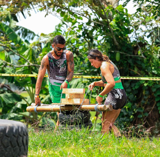Two adults engage in a challenging outdoor team-building exercise with wooden obstacles.