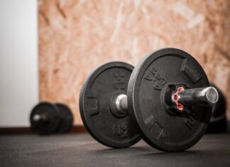 Como emagrecer sem perder massa muscular: Descubra o segredo Rustic gym scene showing close-up of dumbbells for weight training.