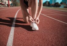 Close-up of a woman tying her shoes on a running track, ready to sprint.