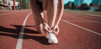 Close-up of a woman tying her shoes on a running track, ready to sprint.