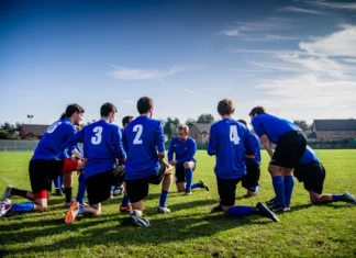 Como funciona a fase de grupos da Liga Europa UEFA A group of male football players in blue uniforms huddle on a grassy field before a match.