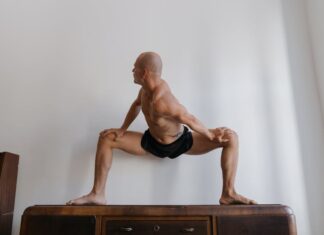 Como ganhar massa muscular com treino em casa Bald man in athletic wear performing a yoga pose indoors, highlighting strength and flexibility.