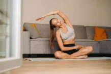 Woman practicing yoga on a mat in a cozy living room setting.