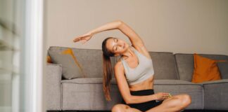 Woman practicing yoga on a mat in a cozy living room setting.