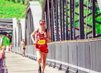 Como melhorar desempenho em corridas de longa distância Runner in a bright marathon, displaying endurance and athleticism on a sunny day bridge course.