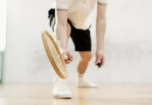 Close-up of a squash player swinging their racket indoors with dynamic motion.