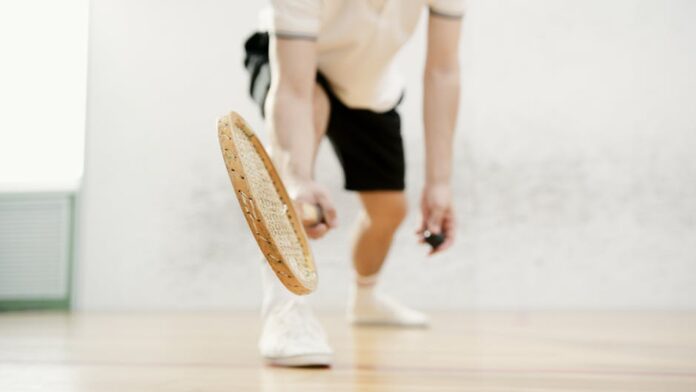 Close-up of a squash player swinging their racket indoors with dynamic motion.