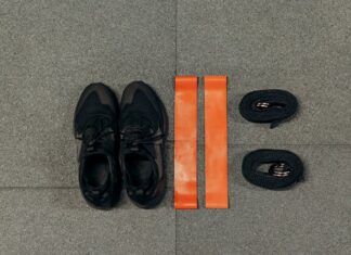 Como perder peso praticando desporto ao ar livre Flat lay of fitness essentials: sneakers, resistance bands, and straps for training.