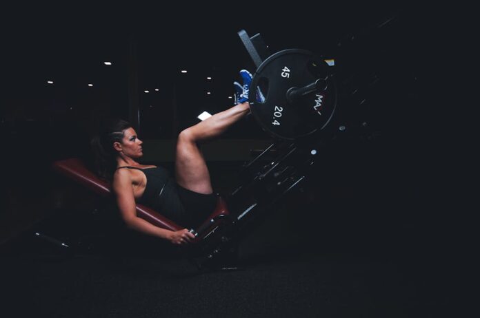 A woman engages in an intense leg press workout at the gym, showcasing strength and fitness.