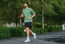 A confident young man jogging in a green park, enjoying a healthy lifestyle.
