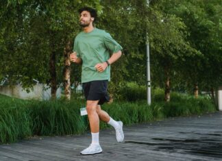 A confident young man jogging in a green park, enjoying a healthy lifestyle.