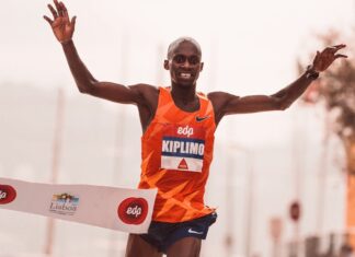 Runner crossing the finish line at a marathon in Lisbon, showcasing victory and achievement.
