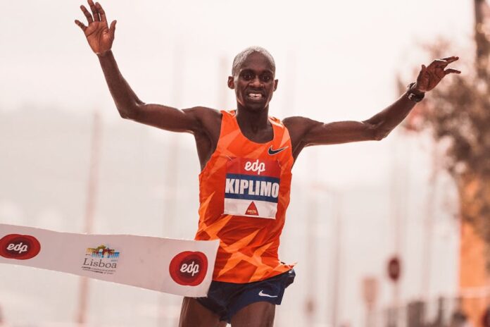 Runner crossing the finish line at a marathon in Lisbon, showcasing victory and achievement.