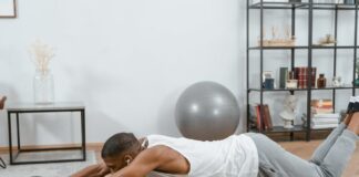 Man using an ab roller on a yoga mat indoors, promoting fitness and healthy lifestyle.