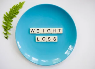 Desporto faz bem à saúde: Descubra os benefícios A blue plate with 'weight loss' tiles and a fern leaf on white background.