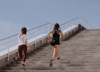 Two women running up stairs outdoors, embodying fitness and wellness.