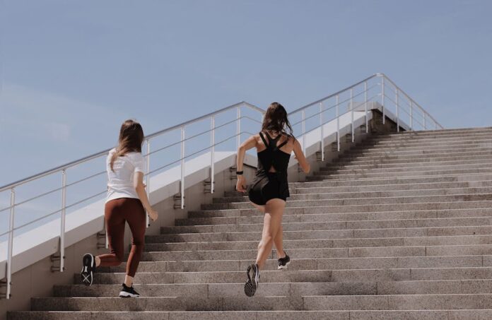 Two women running up stairs outdoors, embodying fitness and wellness.