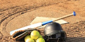 Close-up of baseball and softball gear on a dirt field, ready for a game.