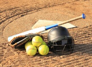 Close-up of baseball and softball gear on a dirt field, ready for a game.