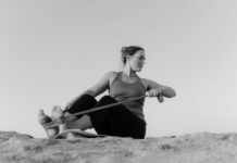 A woman practicing yoga with a resistance band on a beach in black and white.