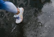 Close-up of a runner's shoe splashing through a puddle on a rainy day.