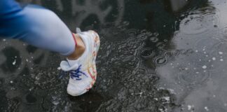 Close-up of a runner's shoe splashing through a puddle on a rainy day.