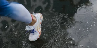 Close-up of a runner's shoe splashing through a puddle on a rainy day.
