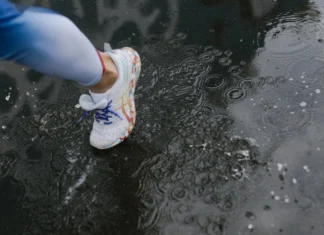 Close-up of a runner's shoe splashing through a puddle on a rainy day.