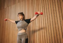 Caucasian woman in activewear lifting dumbbells for fitness training.