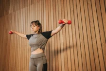 Caucasian woman in activewear lifting dumbbells for fitness training.