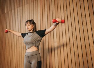 Caucasian woman in activewear lifting dumbbells for fitness training.
