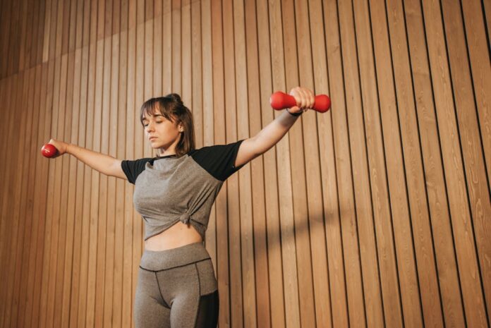 Caucasian woman in activewear lifting dumbbells for fitness training.