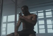 A dedicated athlete uses a massage gun to relax his muscles post-workout in the gym.