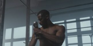 A dedicated athlete uses a massage gun to relax his muscles post-workout in the gym.