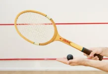Detailed view of a squash racket and ball in hand, indoor sports scene.