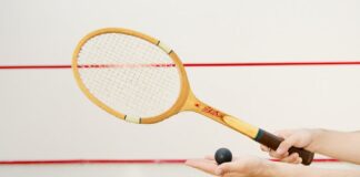 Detailed view of a squash racket and ball in hand, indoor sports scene.