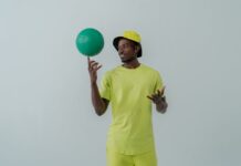 Tendências atuais no mundo do desporto que vão surpreender Portrait of a man in neon green clothing spinning a green ball indoors.