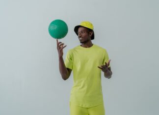 Tendências atuais no mundo do desporto que vão surpreender Portrait of a man in neon green clothing spinning a green ball indoors.