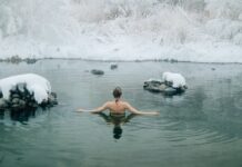 Benefícios da natação para articulações: Conhece Todos? A young woman enjoying a swim in a tranquil winter lake surrounded by snow.