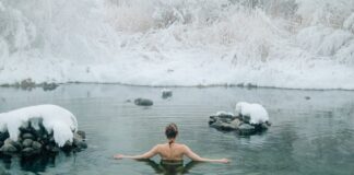 Benefícios da natação para articulações: Conhece Todos? A young woman enjoying a swim in a tranquil winter lake surrounded by snow.