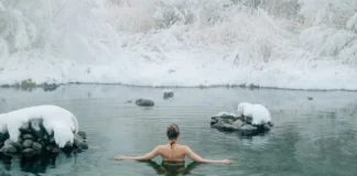 A young woman enjoying a swim in a tranquil winter lake surrounded by snow.