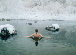 A young woman enjoying a swim in a tranquil winter lake surrounded by snow.