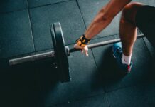 Close-up of a person lifting a barbell in an indoor gym, focusing on strength training.