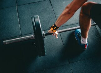 Close-up of a person lifting a barbell in an indoor gym, focusing on strength training.