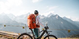 Equipamento essencial para ciclistas iniciantes: O que não pode faltar Cyclist with backpack enjoying a scenic mountain view in Saas-Fee, Switzerland.