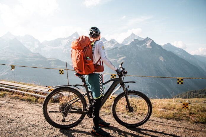 Equipamento Essencial para Ciclistas Iniciantes: O Que Não Faltar! Cyclist with backpack enjoying a scenic mountain view in Saas-Fee, Switzerland.