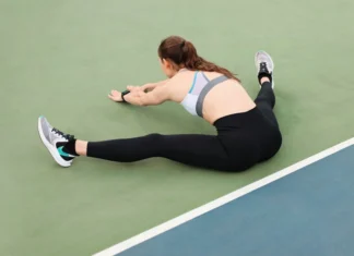 Young woman in activewear stretching on a tennis court for workout.