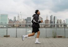 Adult man jogging along a waterfront with the New York City skyline in the background, exuding a vibrant urban lifestyle.