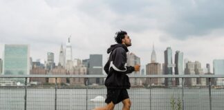 Adult man jogging along a waterfront with the New York City skyline in the background, exuding a vibrant urban lifestyle.