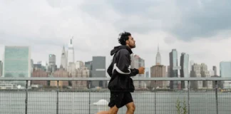 Adult man jogging along a waterfront with the New York City skyline in the background, exuding a vibrant urban lifestyle.